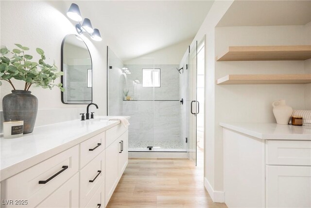 bathroom featuring a shower stall, vanity, wood finished floors, and lofted ceiling