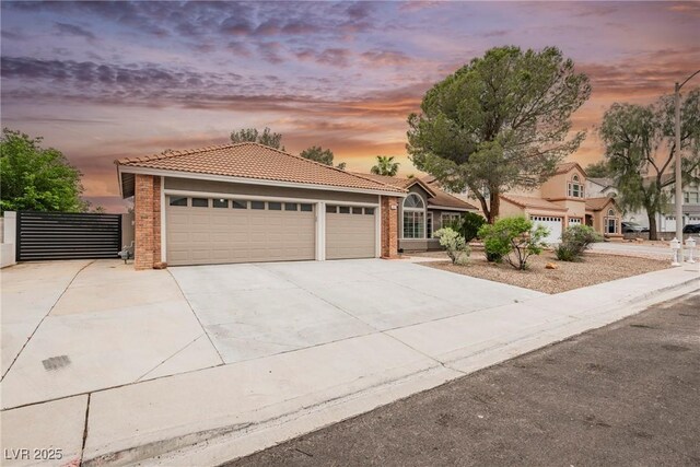 view of front of property with a tile roof, brick siding, concrete driveway, and a garage