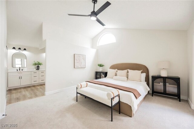 bedroom with light colored carpet, high vaulted ceiling, ensuite bath, a sink, and baseboards