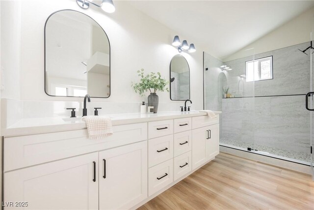 full bathroom featuring lofted ceiling, a stall shower, double vanity, and wood finished floors