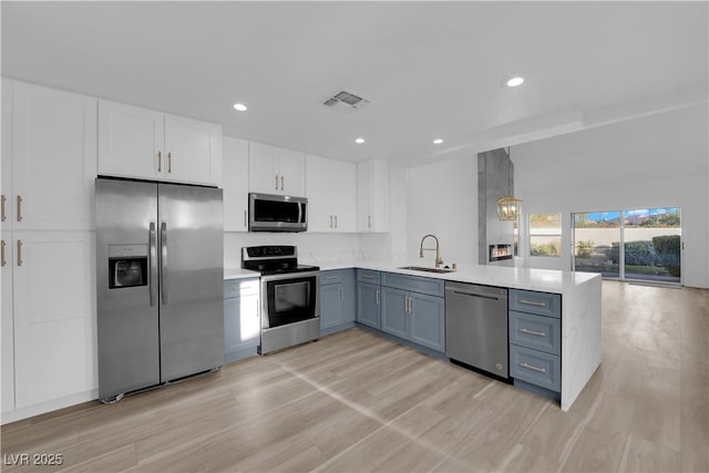6940 Emerald Springs Ln, Las Vegas, NV 89113 - kitchen featuring stainless steel appliances, a sink, white cabinets, a peninsula, and light countertops