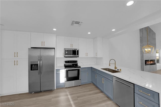 6940 Emerald Springs Ln, Las Vegas, NV 89113 - kitchen with stainless steel appliances, a sink, white cabinets, recessed lighting, and light stone countertops