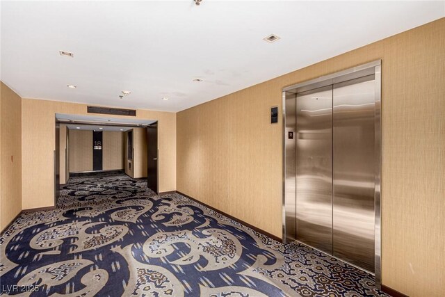 corridor with elevator, baseboards, and carpet floors