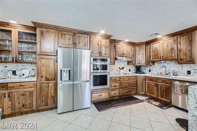 5202 Willis St, North Las Vegas, NV 89031 - kitchen featuring stainless steel appliances, a sink, light tile patterned floors, decorative backsplash, and a textured ceiling
