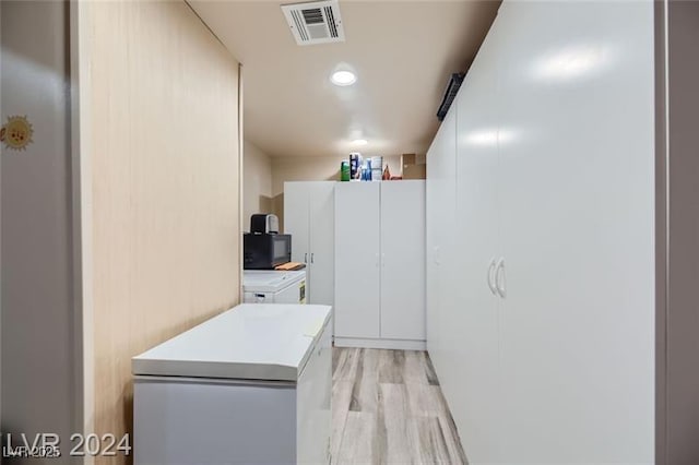 5202 Willis St, North Las Vegas, NV 89031 - kitchen featuring fridge, independent washer and dryer, black microwave, light countertops, and light wood-type flooring