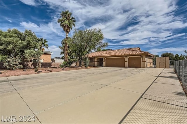 5202 Willis St, North Las Vegas, NV 89031 - mediterranean / spanish-style house with a garage, fence, driveway, stucco siding, and a tile roof