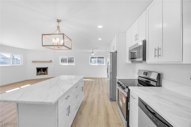 1616 Yellow Rose St, Las Vegas, NV 89108 - kitchen with appliances with stainless steel finishes, open floor plan, light wood finished floors, a center island, and white cabinets
