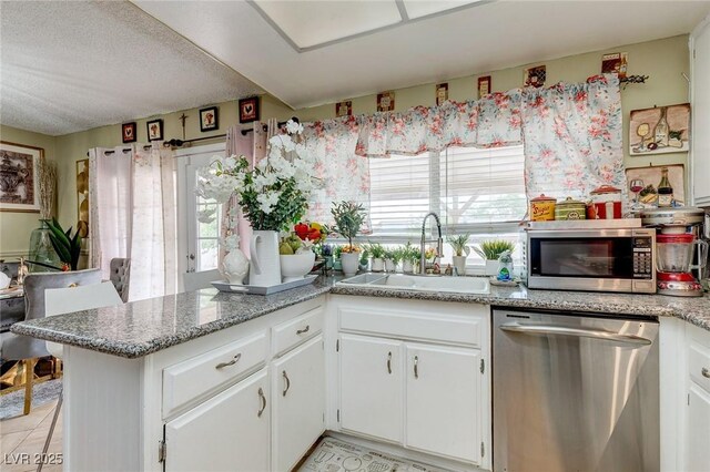 604 N Torrey Pines Dr, Las Vegas, NV 89107 - kitchen with appliances with stainless steel finishes, a sink, white cabinetry, a peninsula, and light tile patterned floors