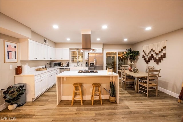2043 Sombrero Dr, Las Vegas, NV 89169 - kitchen featuring stainless steel appliances, a breakfast bar, white cabinets, a center island, and light wood finished floors