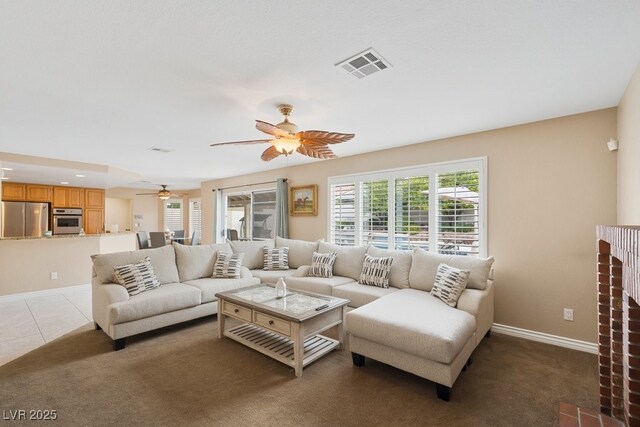 living area with ceiling fan, plenty of natural light, baseboards, and light carpet