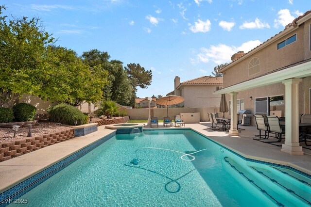 view of swimming pool featuring a patio, a fenced backyard, a pool with connected hot tub, and outdoor dining area