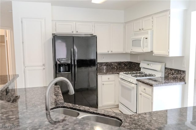 kitchen with white appliances, a sink, dark stone counters, and white cabinetry