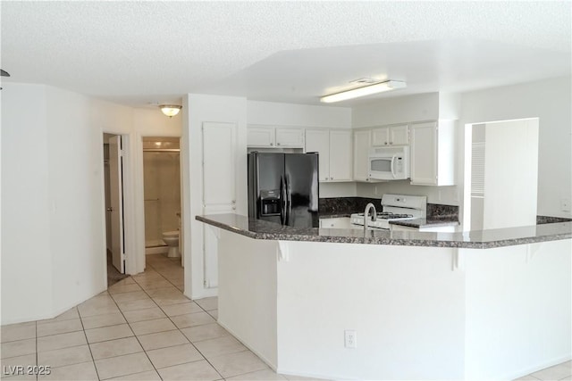 kitchen featuring white appliances, a peninsula, a breakfast bar area, white cabinetry, and light tile patterned floors