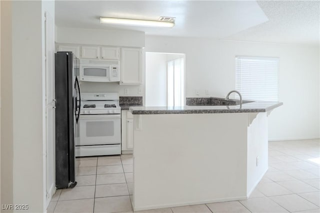 kitchen with white appliances, white cabinets, light tile patterned floors, and a kitchen bar