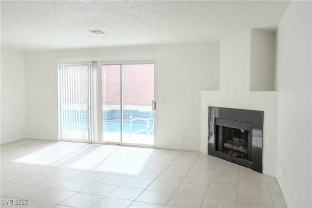unfurnished living room featuring a textured ceiling, light tile patterned floors, and a fireplace
