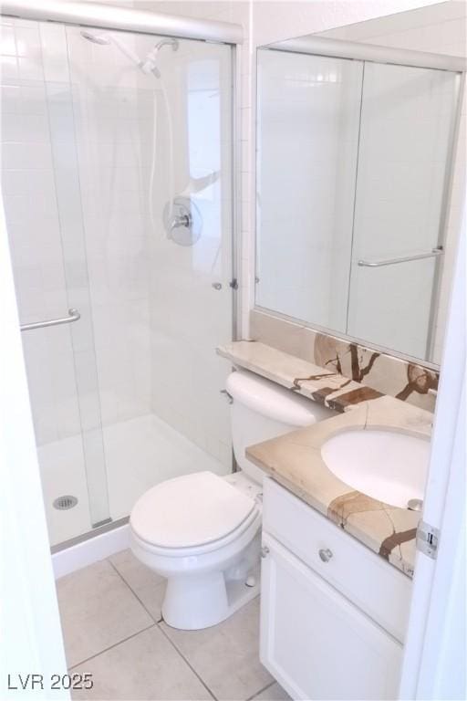 bathroom with a shower stall, vanity, tile patterned flooring, and toilet