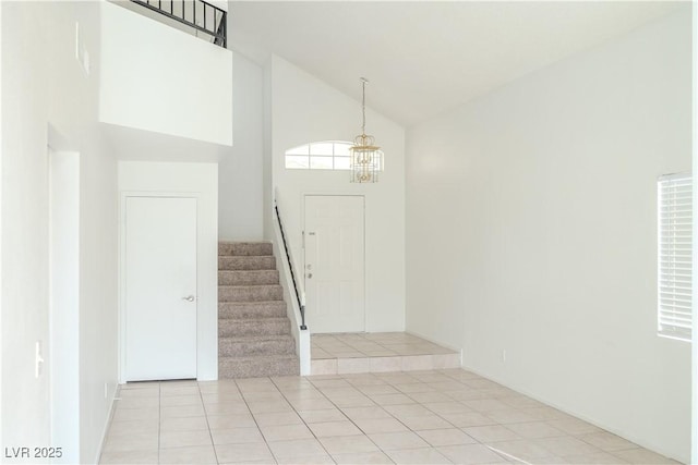 entrance foyer with high vaulted ceiling, stairs, a chandelier, and light tile patterned flooring