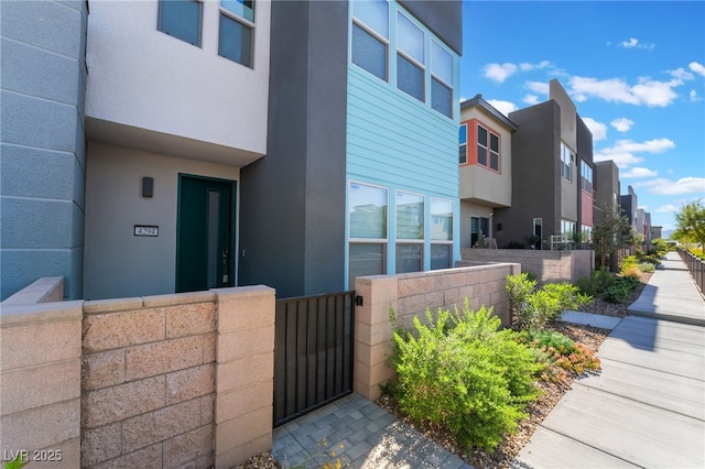 view of home's exterior featuring fence, stucco siding, a gate, and a residential view