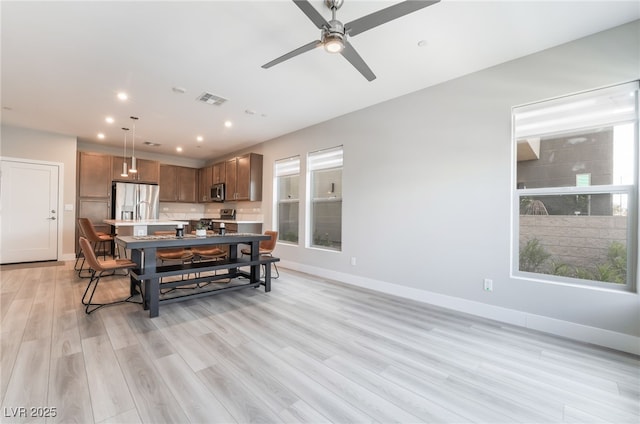 living room featuring a ceiling fan, baseboards, recessed lighting, and light wood-style flooring