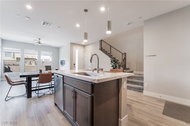 kitchen with a sink, light wood-type flooring, stainless steel dishwasher, dark brown cabinets, and recessed lighting