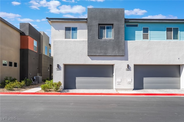 modern home featuring an attached garage, central AC, and stucco siding