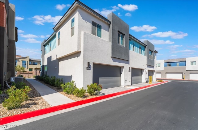 view of property exterior with a residential view, an attached garage, stucco siding, and central air condition unit