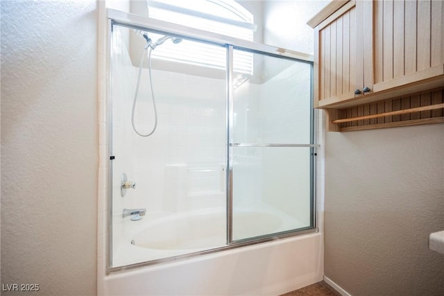 full bathroom with a textured wall and enclosed tub / shower combo