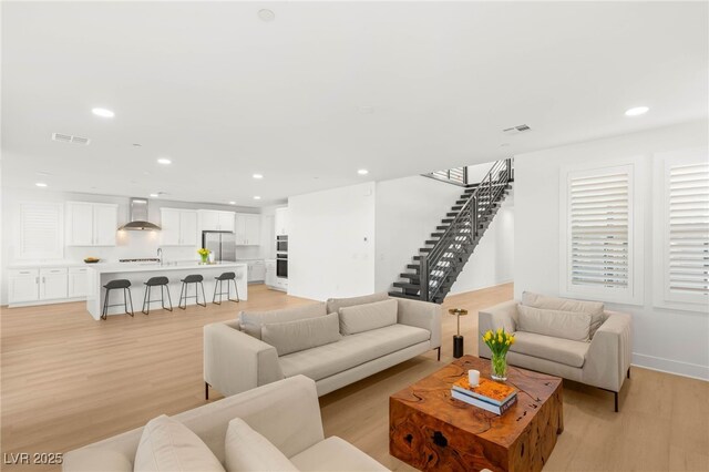 living area with light wood-style flooring, recessed lighting, and stairway