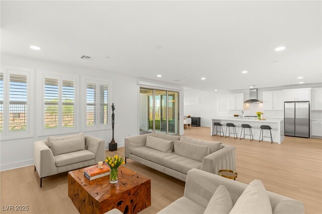 living area featuring light wood-style flooring, recessed lighting, and baseboards