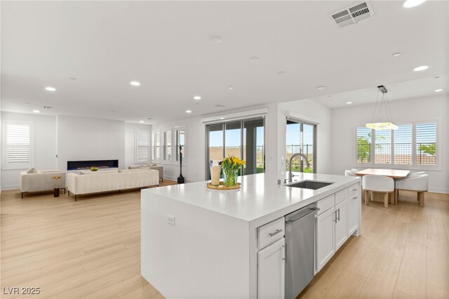 kitchen with a sink, stainless steel dishwasher, recessed lighting, light wood-style flooring, and white cabinets