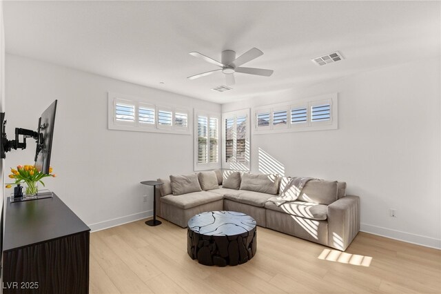 living room featuring ceiling fan, light wood-style floors, and baseboards