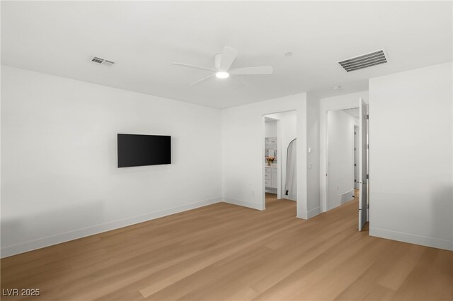unfurnished bedroom featuring light wood-type flooring, baseboards, a ceiling fan, and arched walkways