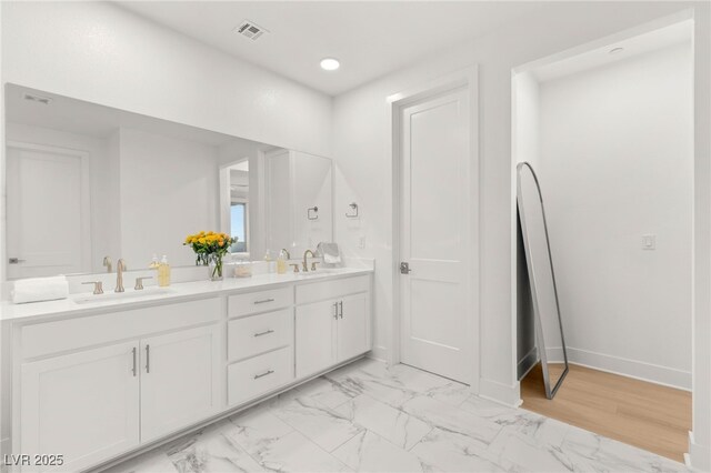 full bath featuring double vanity, recessed lighting, marble look tiles, and baseboards