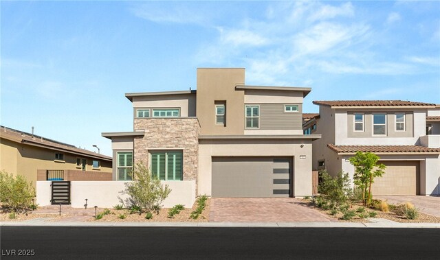 contemporary house with stucco siding, a garage, stone siding, and driveway