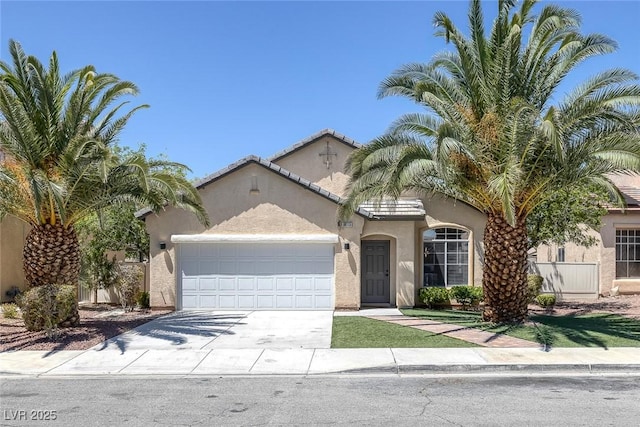 mediterranean / spanish-style home with an attached garage, stucco siding, and driveway