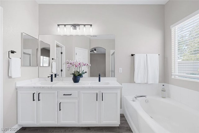full bathroom featuring a garden tub, ceiling fan, and double vanity