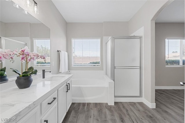 bathroom with a bath, a shower stall, wood finished floors, and vanity
