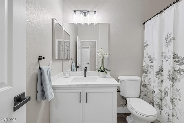 bathroom with toilet, vanity, a textured wall, and a shower with shower curtain