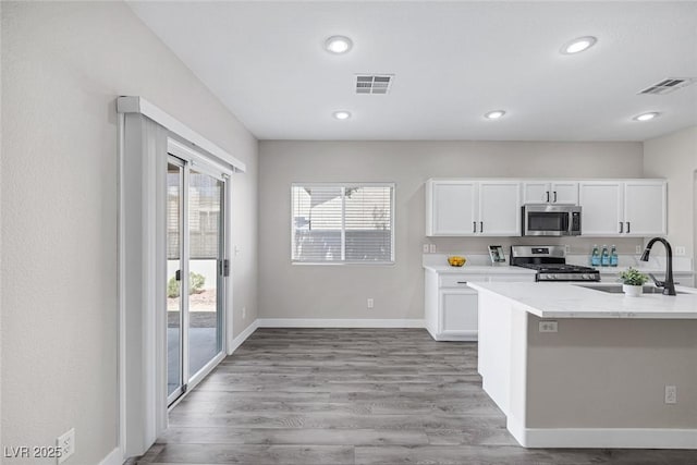 kitchen with stainless steel appliances, a sink, light countertops, white cabinetry, and recessed lighting