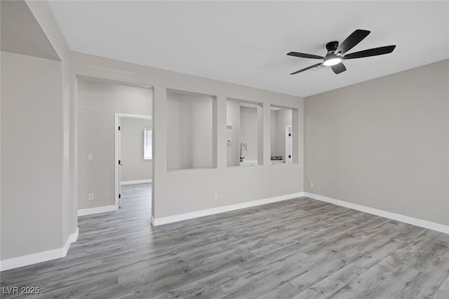 unfurnished living room featuring ceiling fan, wood finished floors, and baseboards