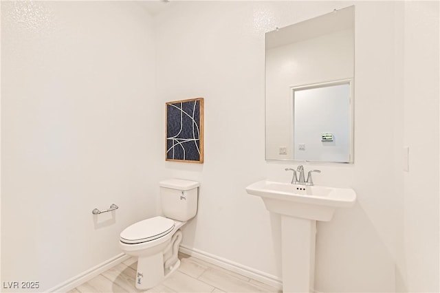 half bath featuring toilet and baseboards