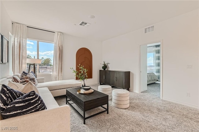 carpeted living area with arched walkways and baseboards