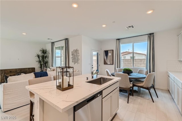 kitchen featuring dishwasher, a sink, open floor plan, healthy amount of natural light, and recessed lighting