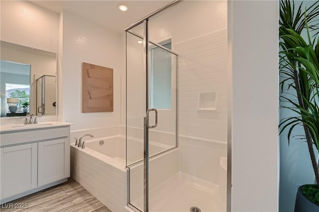 bathroom featuring a bath, vanity, a shower stall, wood finished floors, and recessed lighting