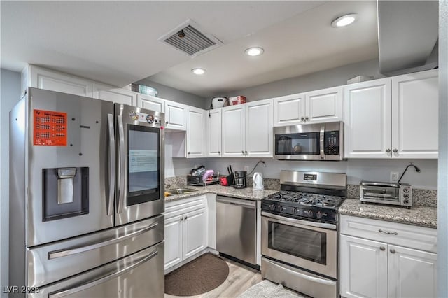 4078 Gold Coast Dr, Las Vegas, NV 89121 - kitchen with stainless steel appliances, white cabinets, light wood finished floors, light stone counters, and recessed lighting