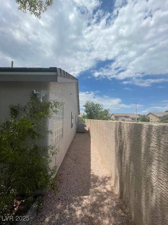 view of home's exterior featuring central air condition unit, fence, and stucco siding