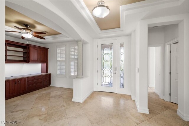 entryway with ornate columns, a raised ceiling, ceiling fan, light tile patterned floors, and baseboards