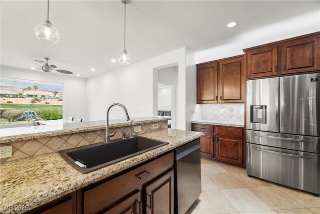 kitchen with stainless steel appliances, a sink, backsplash, light stone counters, and recessed lighting