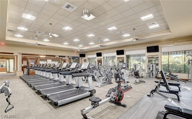 workout area featuring a tray ceiling, carpet, a paneled ceiling, ornate columns, and ornamental molding
