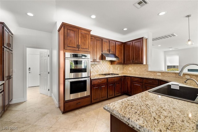 5067 Pensier St, Las Vegas, NV 89135 - kitchen featuring appliances with stainless steel finishes, under cabinet range hood, tasteful backsplash, light stone countertops, and recessed lighting